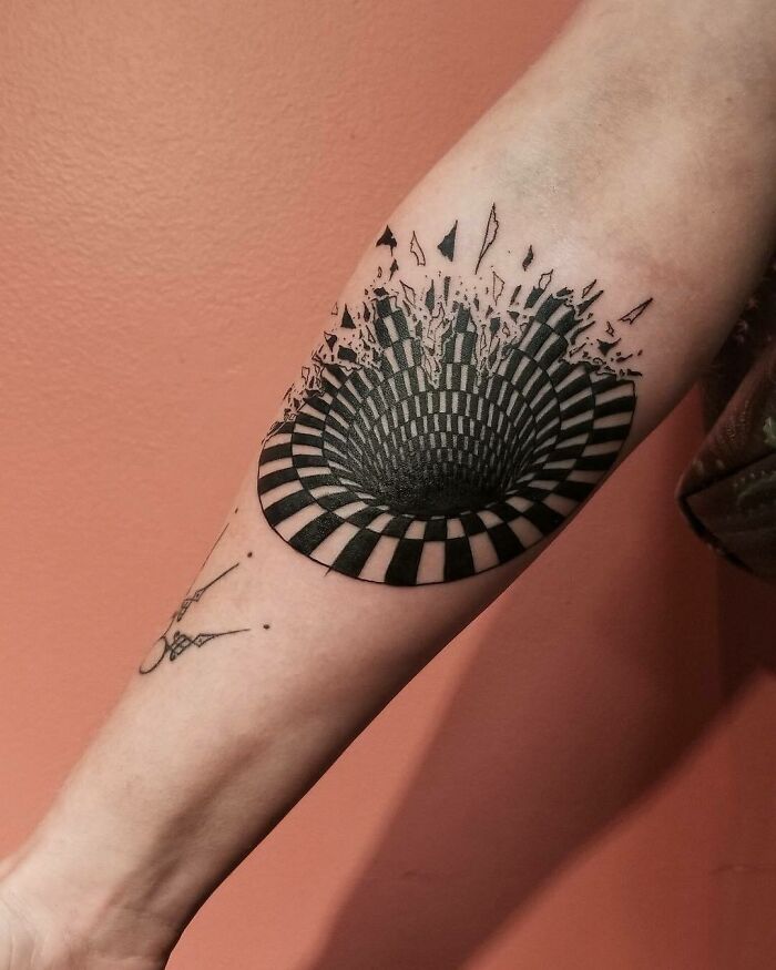 Optical illusion tattoo design with a 3D effect, appearing as a spiral hole on the forearm.