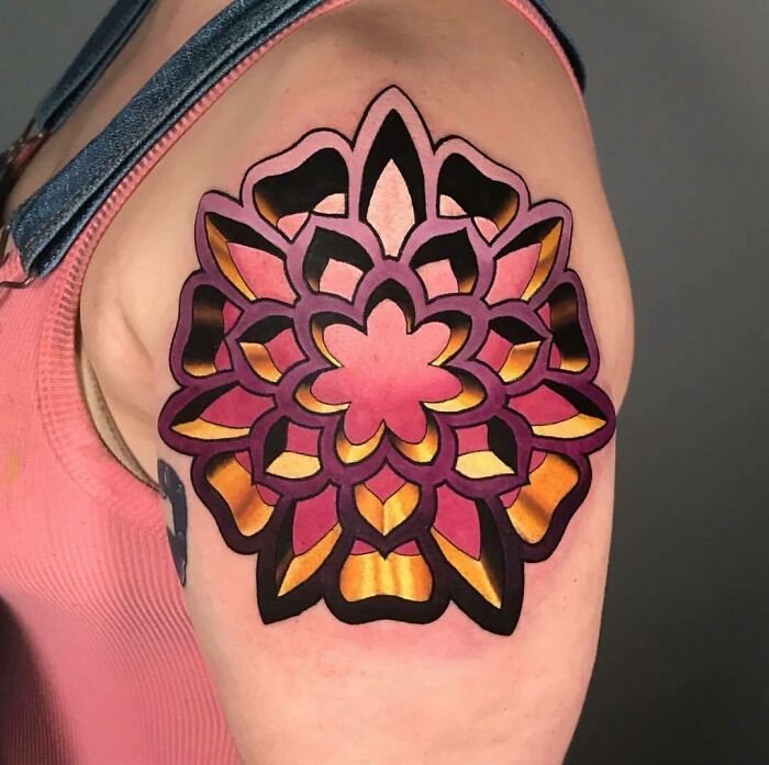 Optical illusion tattoo on arm with vibrant floral mandala design in shades of pink, orange, and black.