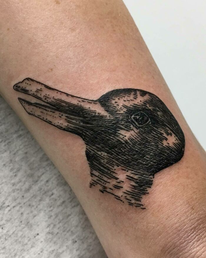 Optical illusion tattoo of a rabbit-duck design on an arm, showcasing mind-bending artistry.