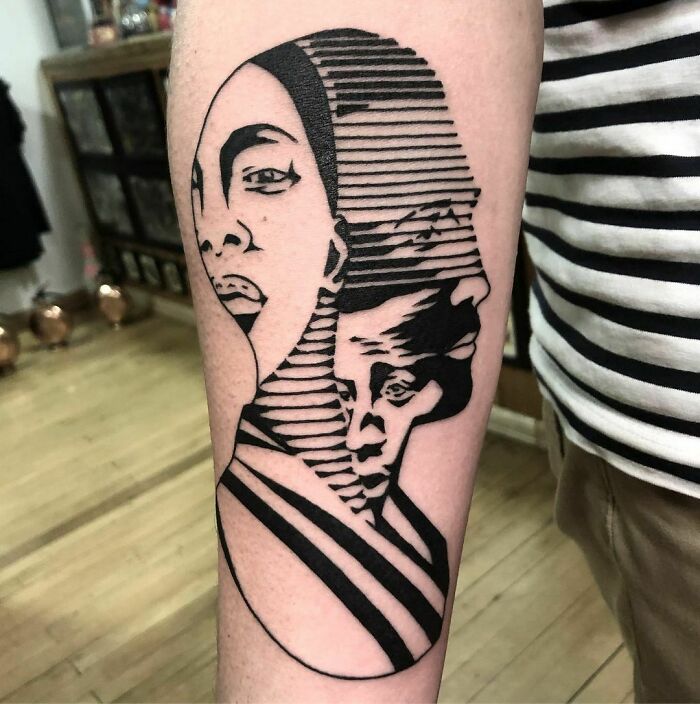 Optical illusion tattoo on arm featuring two overlapping faces in striped design.