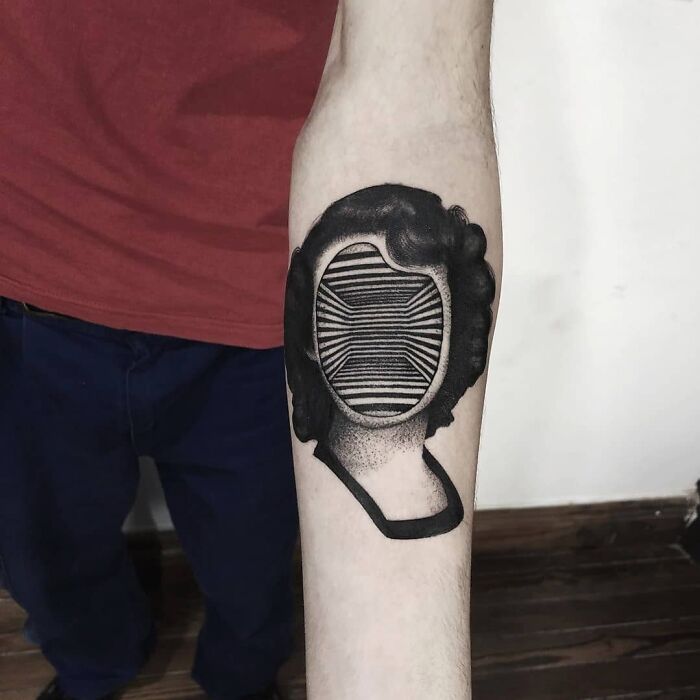 Optical illusion tattoo of a face with striped pattern on a person's forearm, creating an eye-catching visual effect.