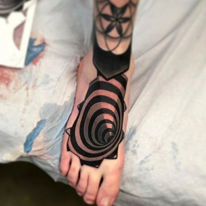 Optical illusion tattoo with a spiral design on a foot, creating a mind-bending effect.
