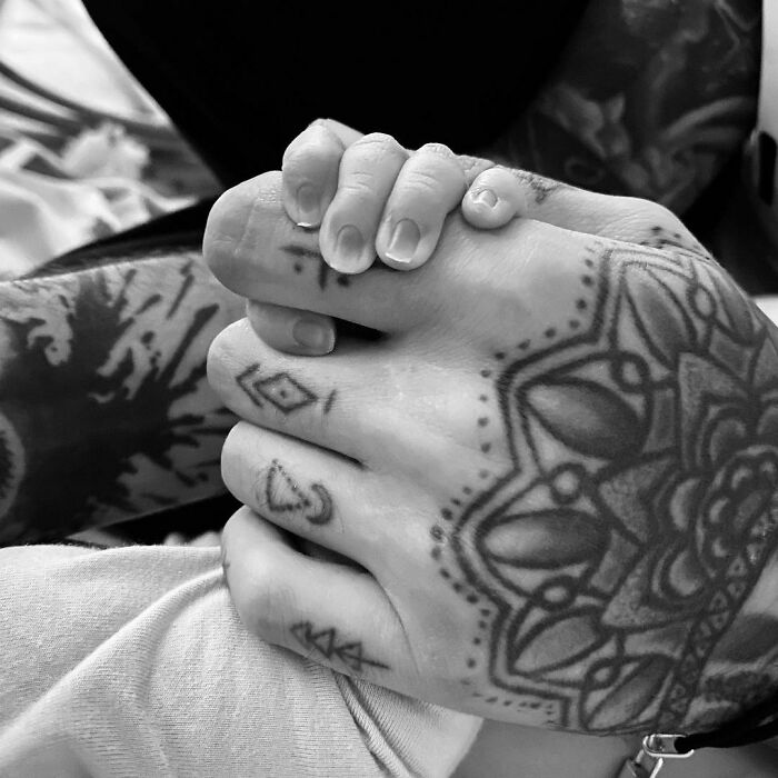 Celebrity tattoos on intertwined hands, showcasing intricate designs, perfect for tattoo inspiration.