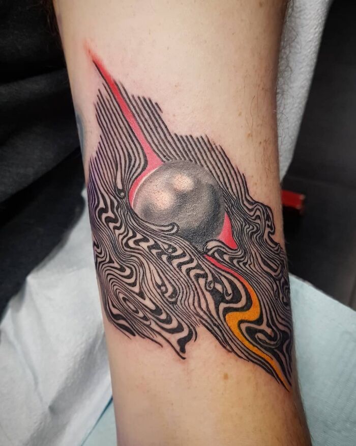Optical illusion tattoo design featuring swirling patterns and a 3D sphere on forearm.