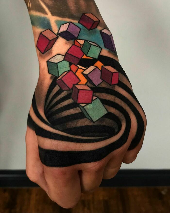 Optical illusion tattoo of 3D cubes and a swirling vortex on a hand, creating a mind-bending visual effect.