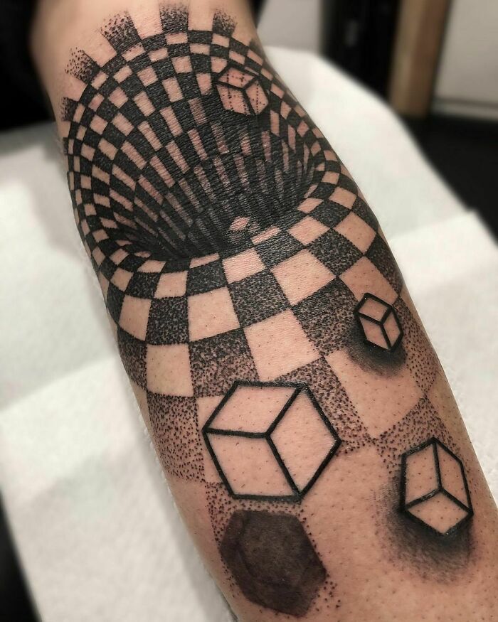Optical illusion tattoo featuring 3D cubes and a spiraling checkered pattern on the forearm.