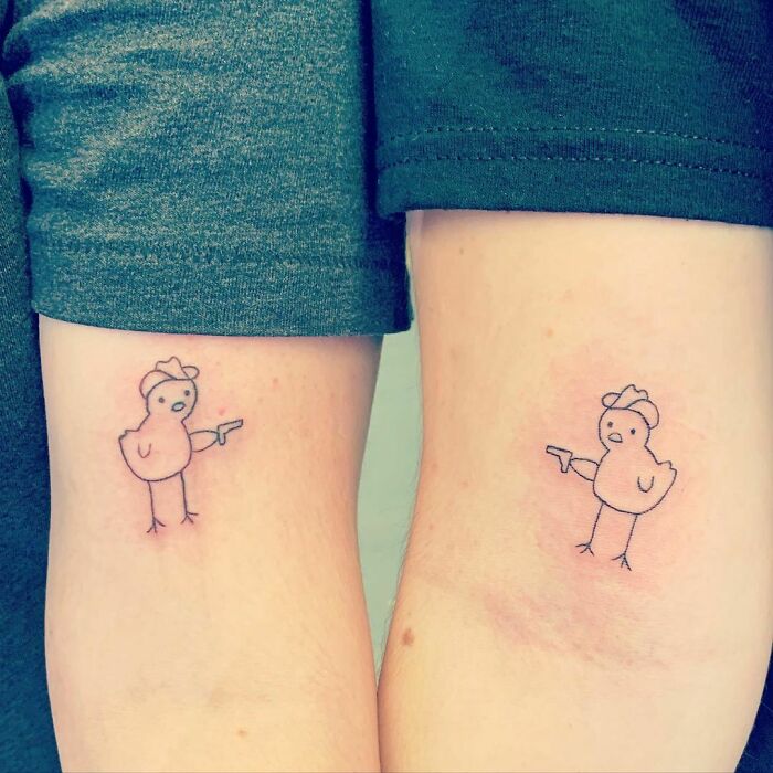 Funny tattoos of cartoon chickens with tiny hats and guns on two arms.