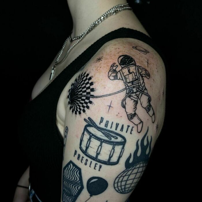 Astronaut optical illusion tattoo design on a person's upper arm, featuring various intricate elements.