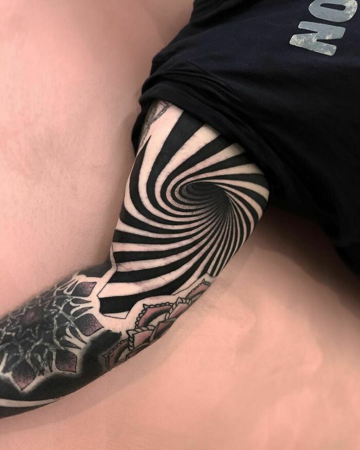 Optical illusion tattoo with spiral design, creating a visual depth effect on the arm.