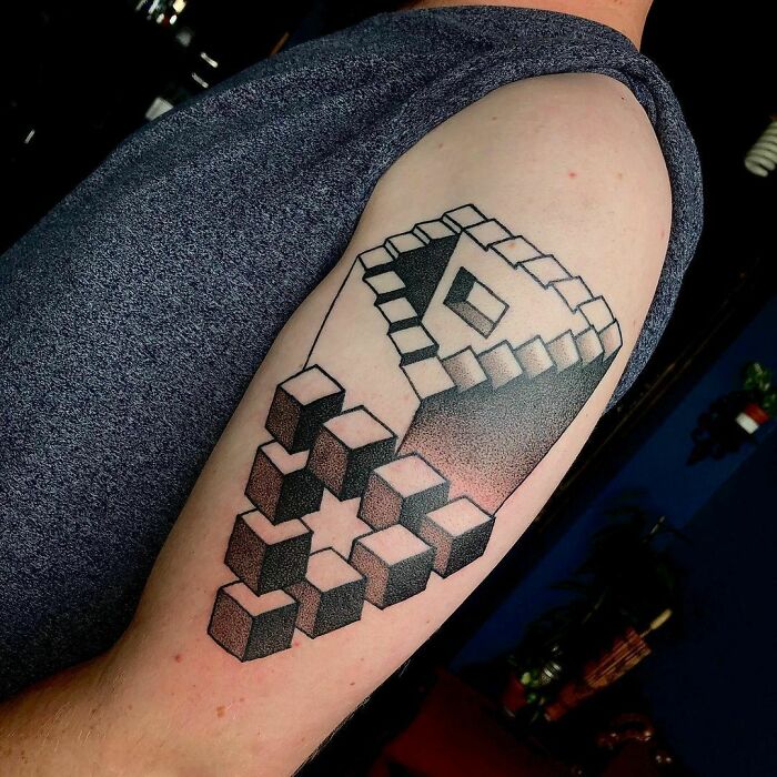 Optical illusion tattoo on arm with 3D cube design creating a mind-bending effect.
