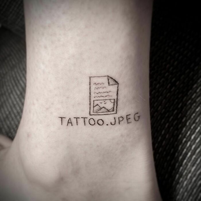 Funny computer file tattoo labeled "TATTOO.JPEG" on a person's leg.