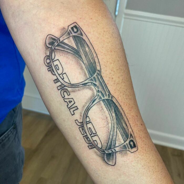 Optical illusion tattoo of 3D glasses on forearm, showcasing creative tattoo design artistry.