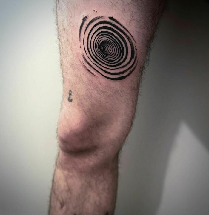 Optical illusion tattoo on leg, featuring a spiral design above the knee.