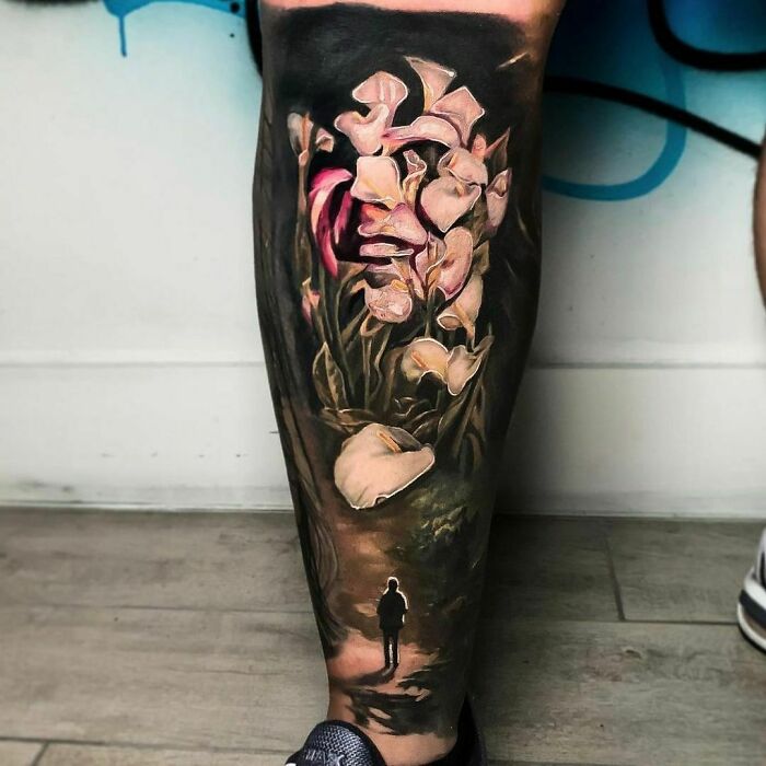 Optical illusion tattoo featuring flowers morphing into a woman's face, creating a mind-bending design on a leg.