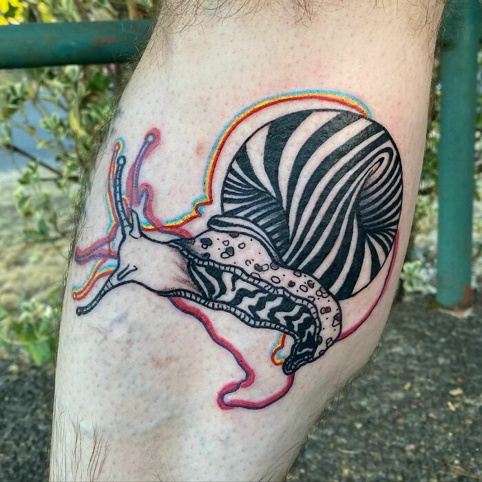 Optical illusion tattoo of a snail with a psychedelic shell design on a person's leg.