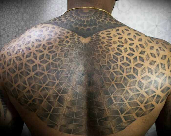 Optical illusion tattoo on a person's back, featuring intricate geometric patterns.