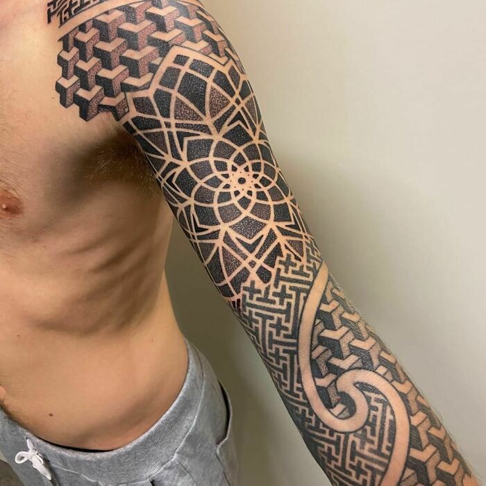 Intricate optical illusion tattoo sleeve with geometric, eye-bending patterns on a person's arm.