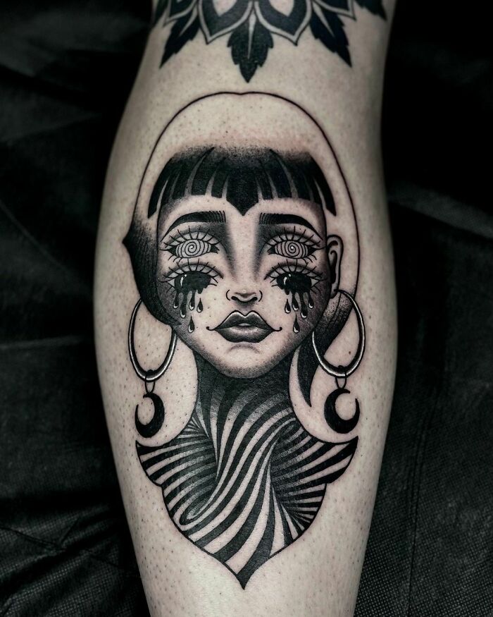 Optical illusion tattoo design featuring a surreal woman's face with teardrop eyes and a swirling neck pattern.