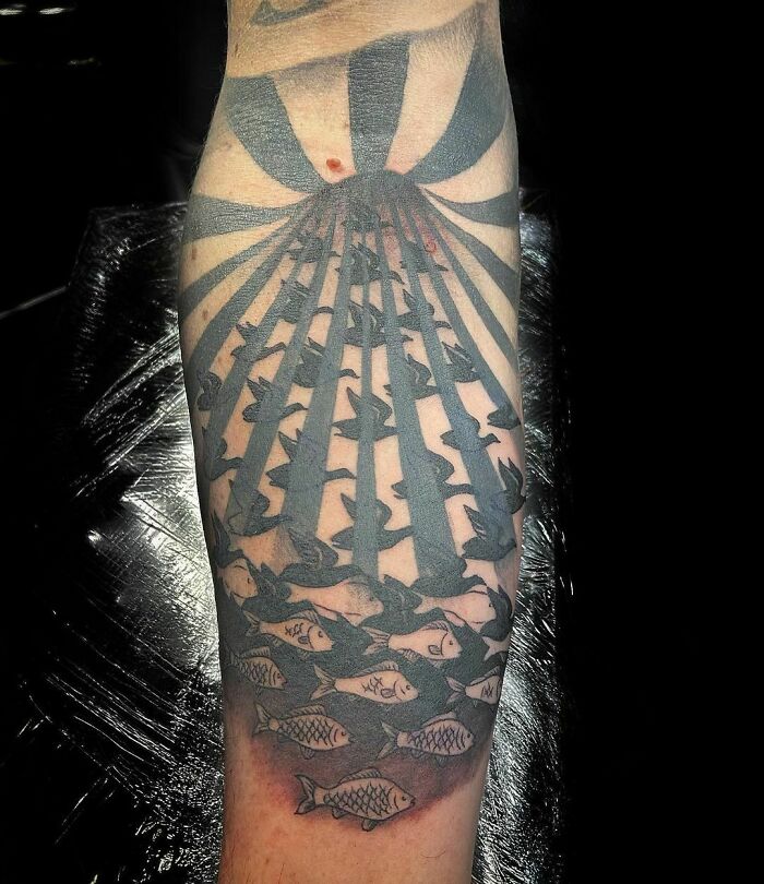 Optical illusion tattoo with birds and fish transforming on forearm.