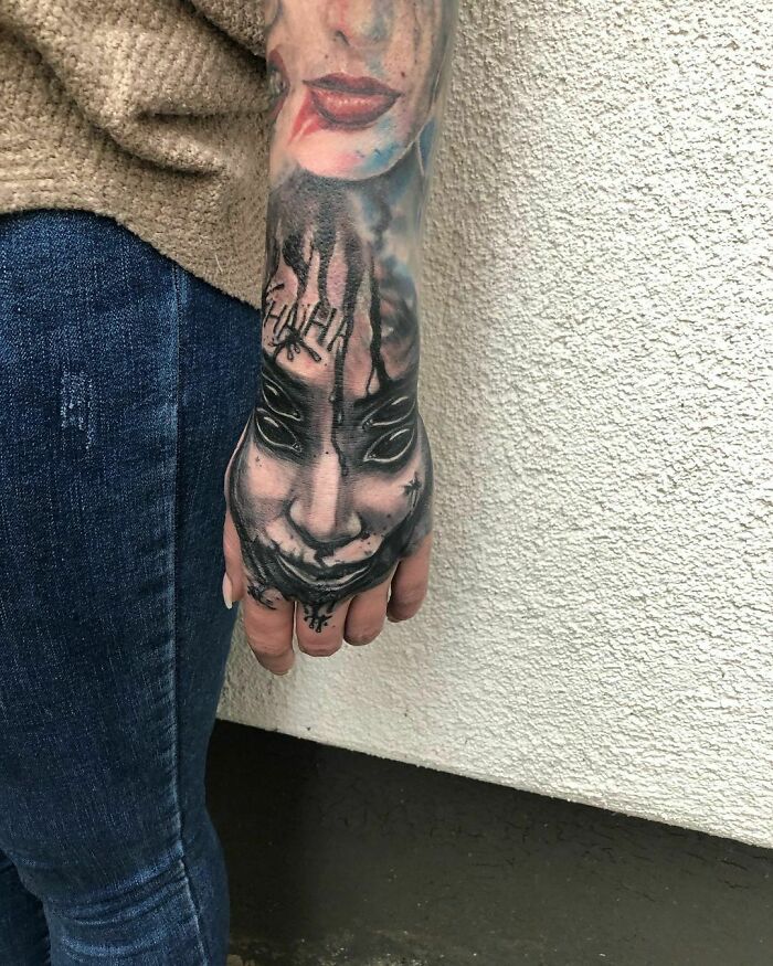 Optical illusion tattoo with a face design on a person's arm, creating a mind-bending visual effect.