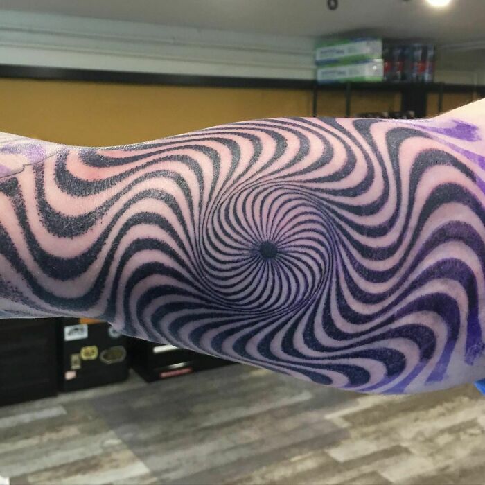 Optical illusion tattoo on an arm with a spiral design creating a mind-bending effect.