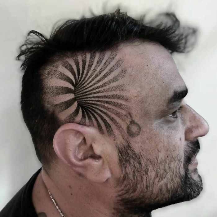 Man with a spiral optical illusion tattoo on shaved side of head, creating a mind-bending design effect.