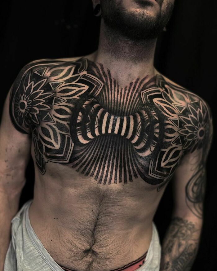 Optical illusion tattoo on man's chest with intricate patterns and lines creating a 3D effect.