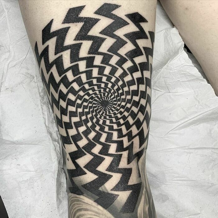 Optical illusion tattoo with a spiral pattern creating a 3D effect on the skin.