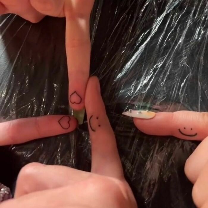 Celebrity tattoos featuring small hearts and smiley faces on fingers.