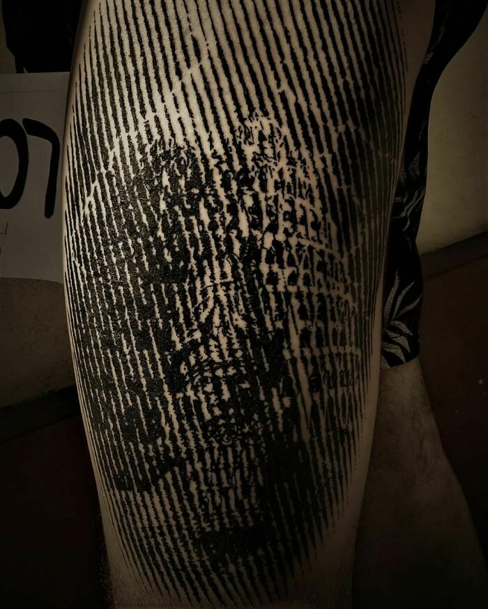 Optical illusion tattoo with intricate lines and hidden face design, creating a mind-bending visual effect.