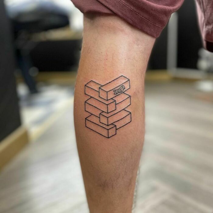 Optical illusion tattoo of stacked blocks on a leg, creating a mind-bending 3D effect.
