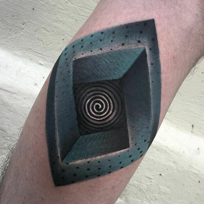 Optical illusion tattoo of a 3D spiral cube on an arm, creating a visual depth effect.