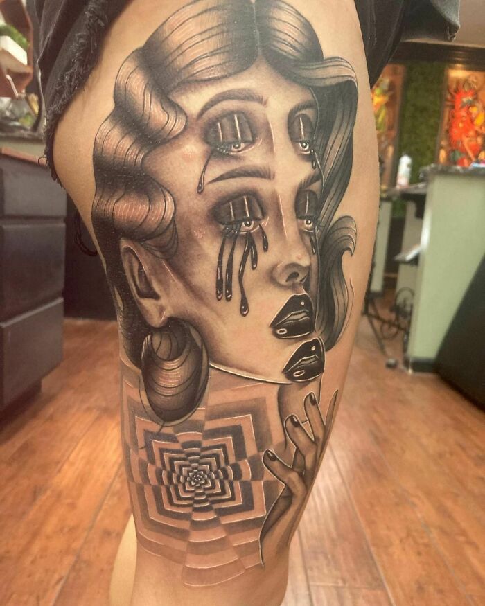 Tattoo of a surreal woman with multiple eyes and tears, showcasing optical illusion and mind-bending design.