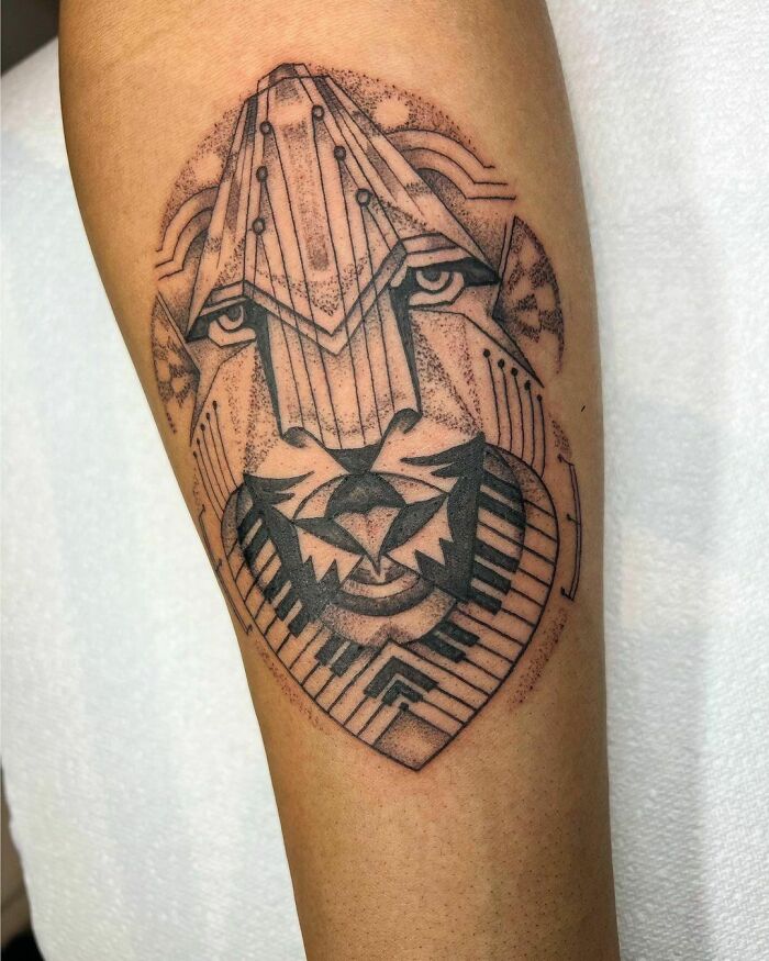 Geometric optical illusion tattoo resembling a lion's face on forearm.