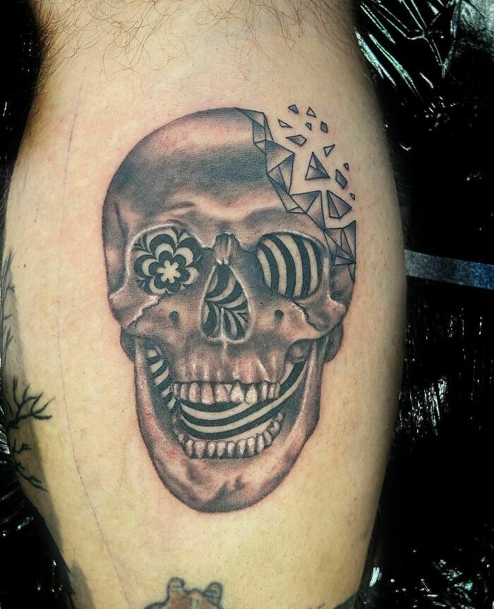 Skull optical illusion tattoo with geometric patterns and intricate shading on forearm.