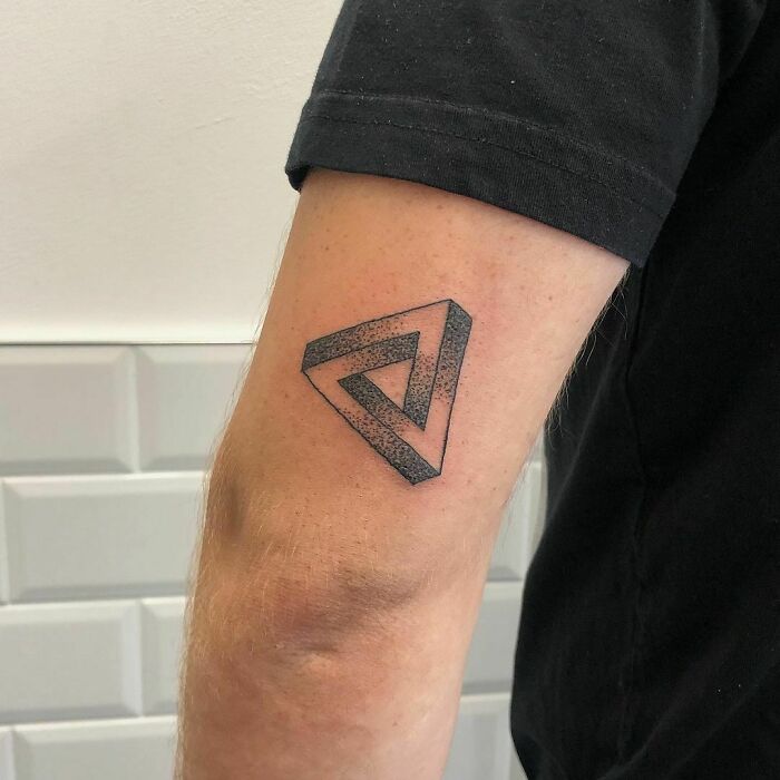 Optical illusion tattoo of a Penrose triangle on a person's arm, playing tricks on eyesight.