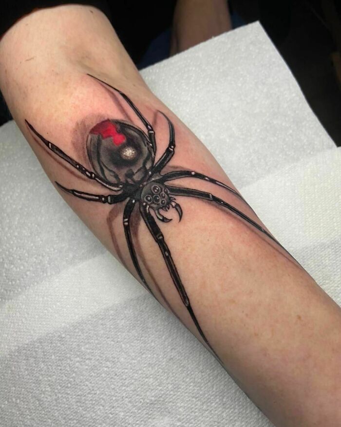 A realistic spider tattoo illusion on an arm, creating a 3D effect.