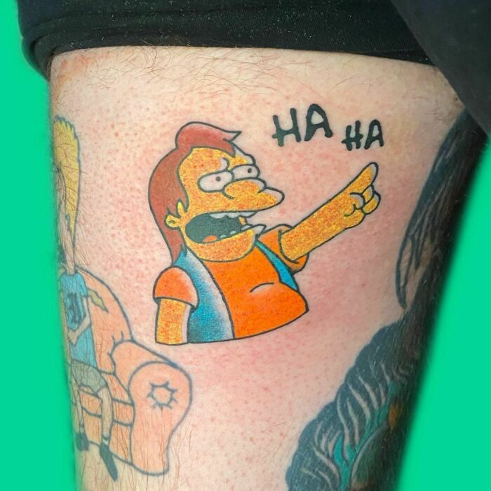 Funny leg tattoo of Simpsons character Nelson pointing and laughing with "Ha Ha" text.