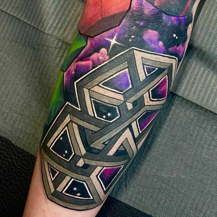 Optical illusion tattoo featuring geometric shapes and vibrant colors on an arm.