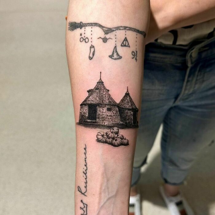 Harry Potter tattoo featuring a broomstick, magical symbols, and Hagrid's hut on a forearm.