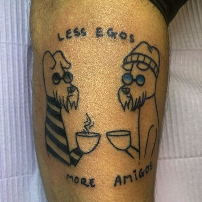 Funny tattoo of two dogs with glasses holding mugs, captioned "Less Egos More Amigos".