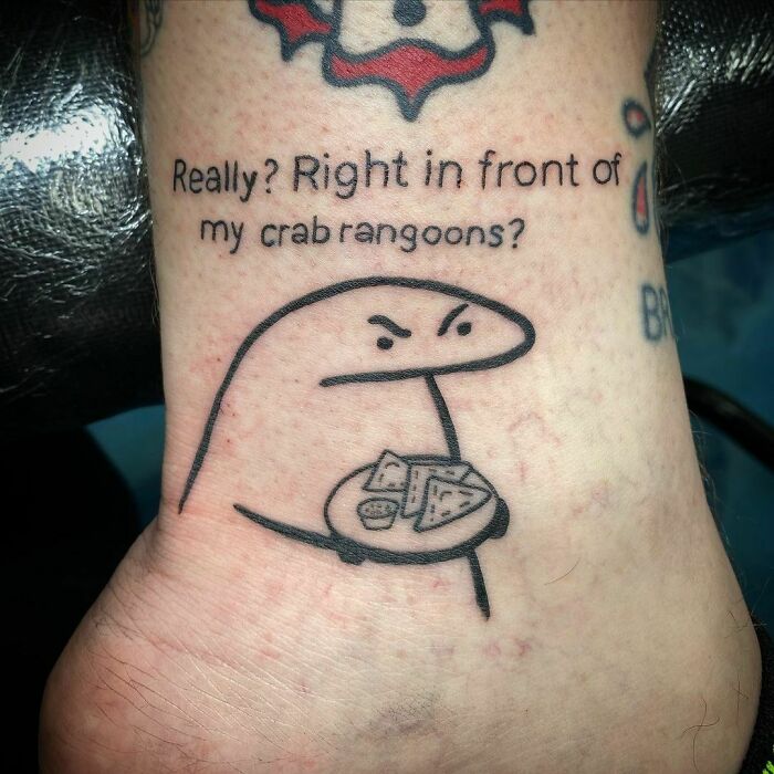 Funny tattoo of an annoyed cartoon character holding food with text about crab rangoons.