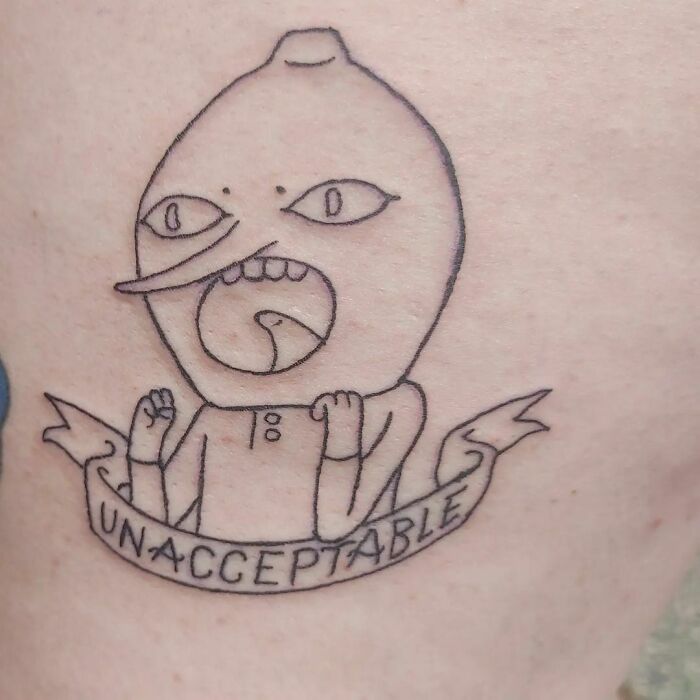 Funny tattoo of a character from Adventure Time with "Unacceptable" banner, showcasing quirky humor.