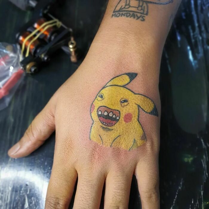 Funny Pikachu hand tattoo with a quirky expression, showcasing unique tattoo art.
