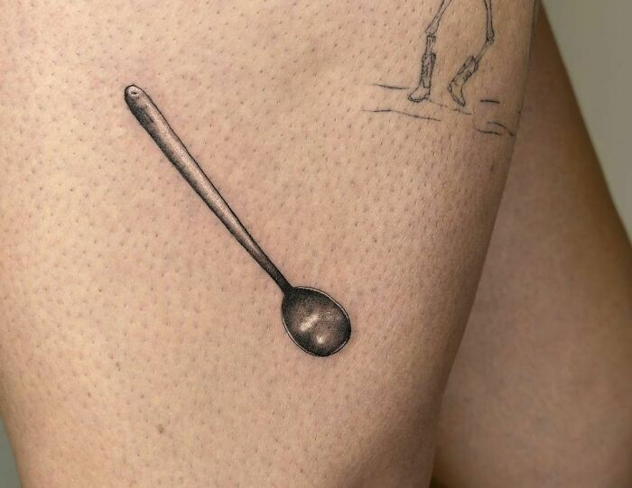 Funny tattoo of a spoon with a sketch nearby on skin.