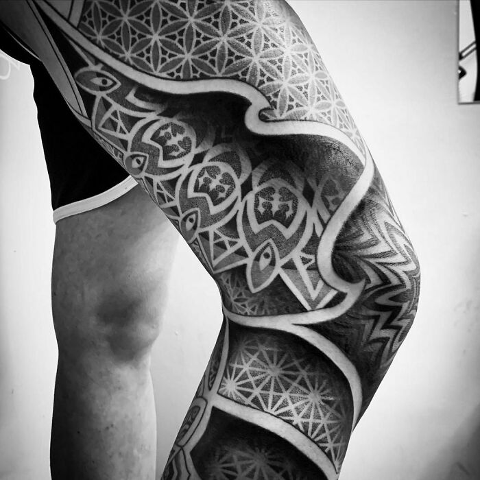 Optical illusion tattoo design on a person's leg, featuring intricate geometric patterns and shading.
