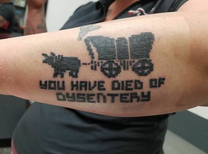Funny hand tattoo of pixelated ox and wagon with humorous text.