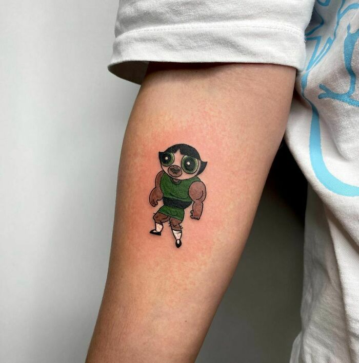 Funny tattoo of a muscular cartoon character on a person's arm.