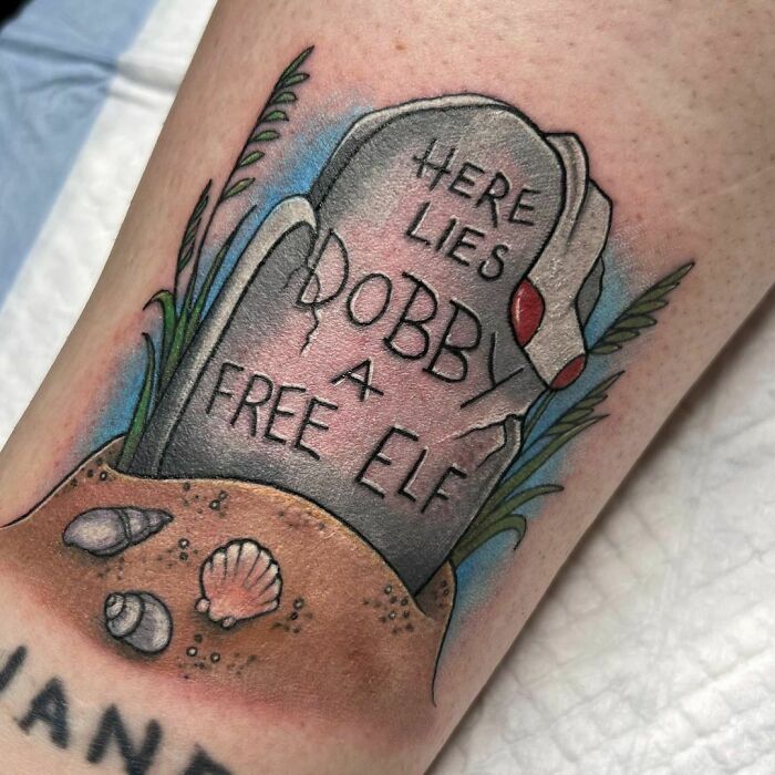 Harry Potter tattoo of Dobby's grave with a sock, featuring shells and grass, for Wizarding World fans.
