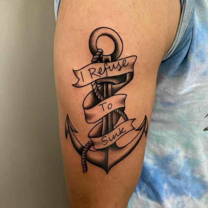 Arm tattoo of an anchor wrapped with a banner reading "I Refuse To Sink," related to attractive tattoo discussions.